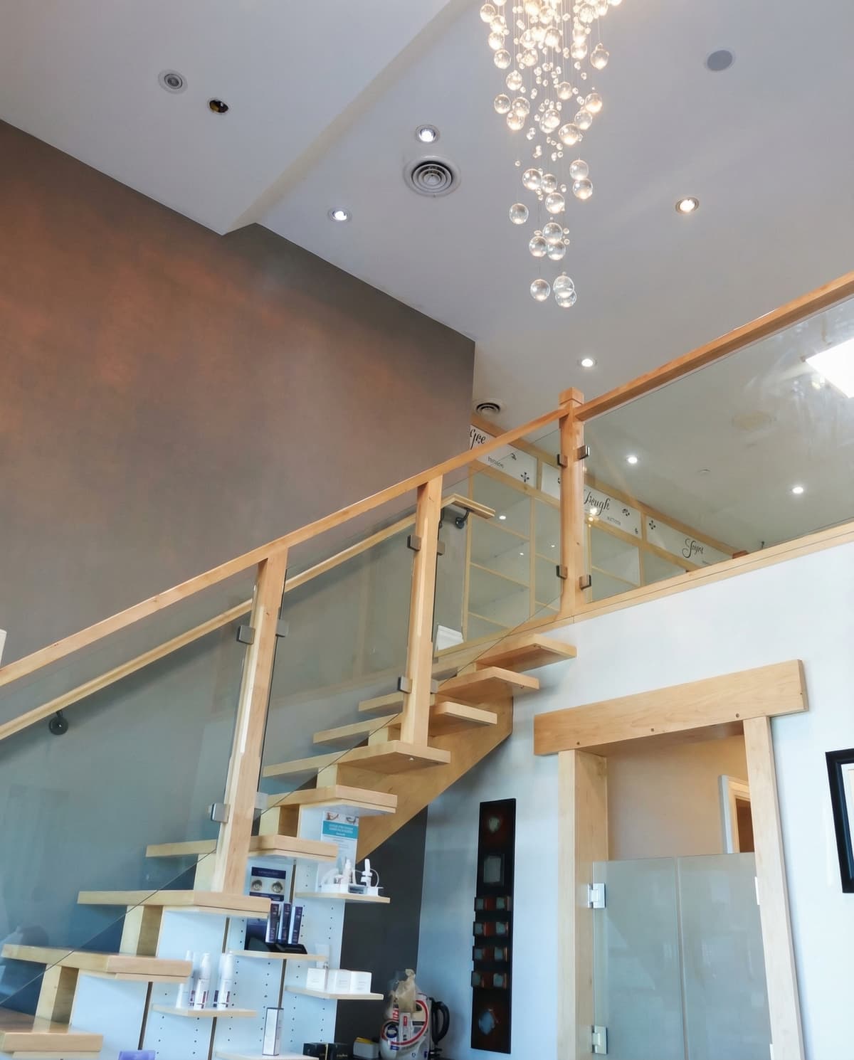 Leslie Med Spa interior — modern staircase with crystal chandelier and product displays